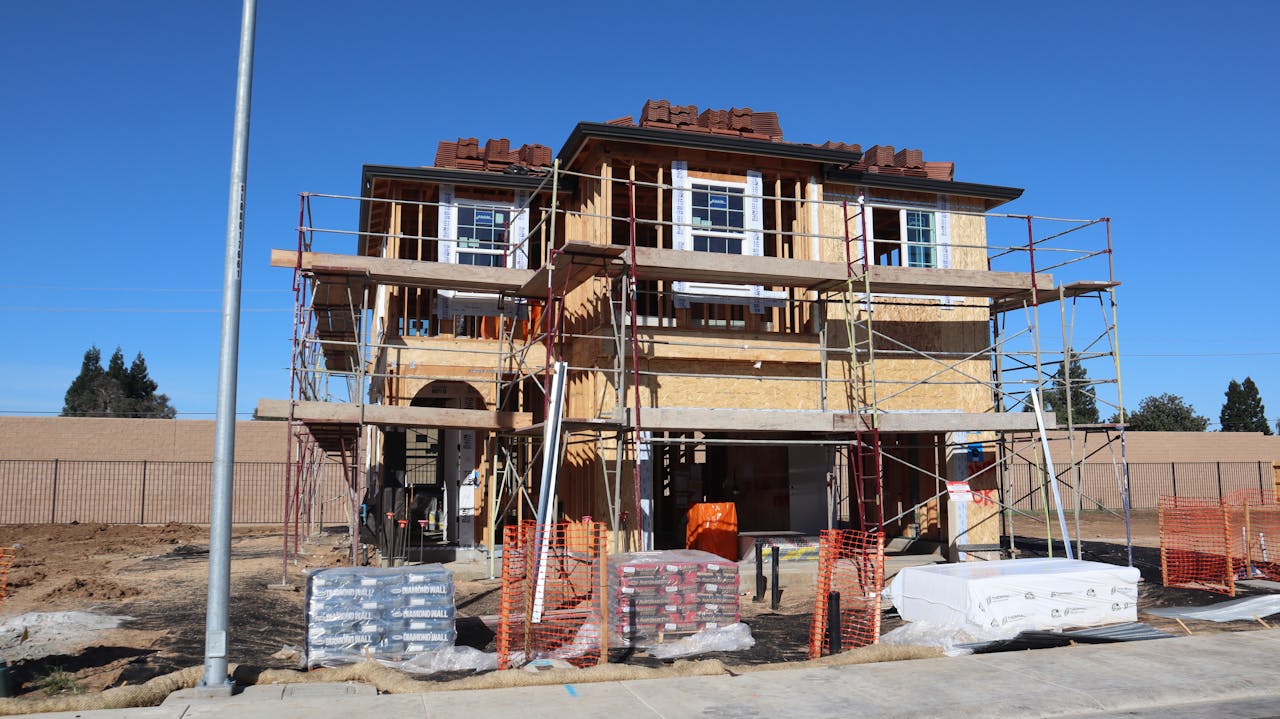 Construction site of a new home development in Elk Grove, California, showcasing scaffolding and materials.