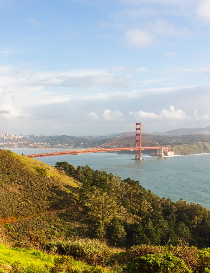 A breathtaking view of the Golden Gate Bridge spanning the San Francisco Bay, framed by lush hills.