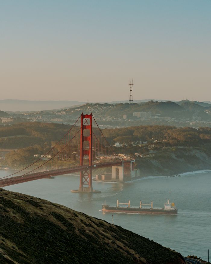 services-04 Stunning view of the Golden Gate Bridge and cargo ship during sunrise in San Francisco Bay.