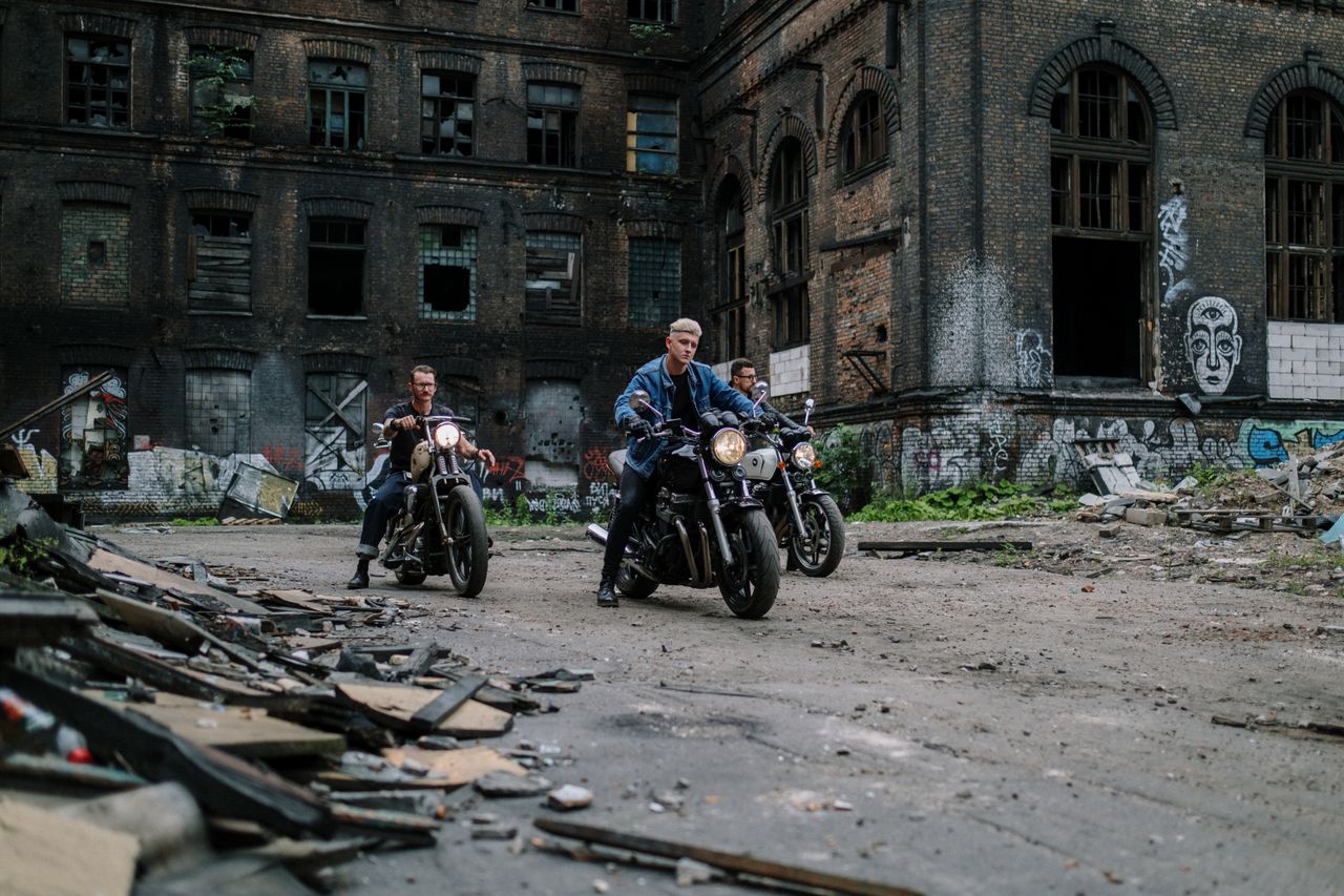 home-img Group of bikers riding motorcycles near an abandoned building with graffiti.