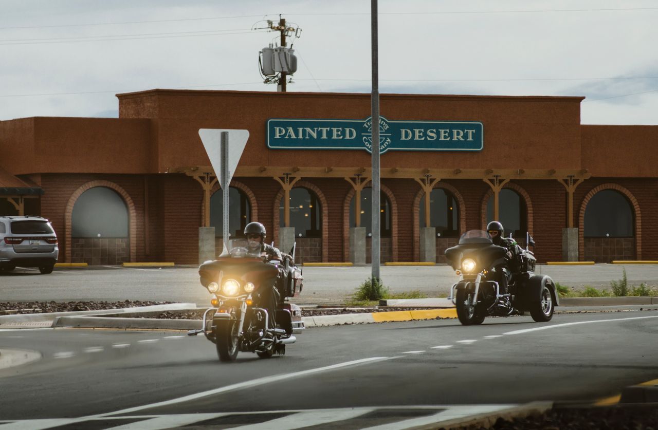 Bikers on a road trip riding through Young, Arizona past the Painted Desert building.